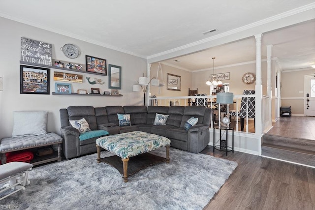 living room with crown molding, a chandelier, visible vents, and wood finished floors