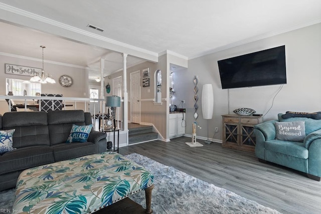 living area featuring visible vents, ornamental molding, wood finished floors, and a chandelier