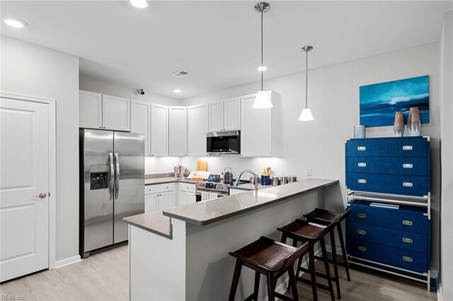 1728 Vankar Dr, Virginia Beach, VA 23456 - kitchen featuring visible vents, light wood-style flooring, a peninsula, stainless steel appliances, and white cabinetry