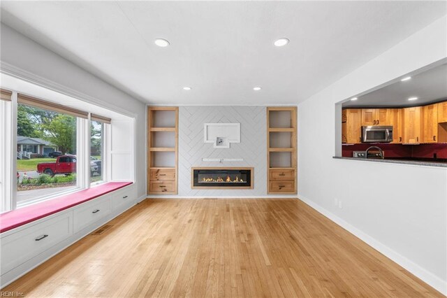 unfurnished living room featuring visible vents, a fireplace, baseboards, light wood-style floors, and recessed lighting