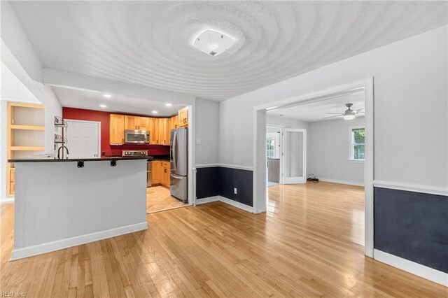 kitchen featuring a ceiling fan, light wood finished floors, appliances with stainless steel finishes, and dark countertops