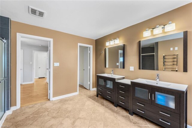 bathroom with visible vents, a sink, baseboards, and two vanities
