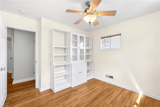 unfurnished bedroom featuring baseboards, a ceiling fan, light wood-style flooring, and visible vents