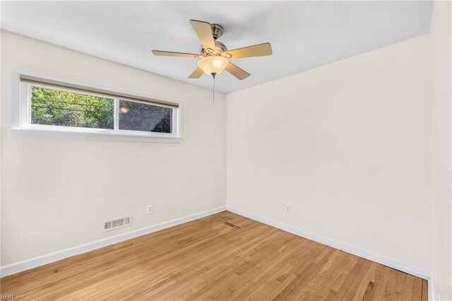 empty room with visible vents, a ceiling fan, baseboards, and light wood-style floors