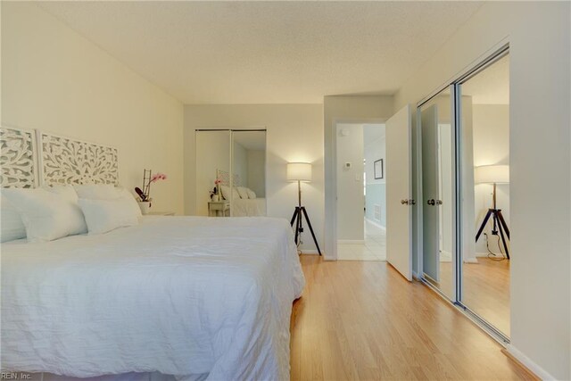 bedroom with baseboards, multiple closets, and light wood-type flooring