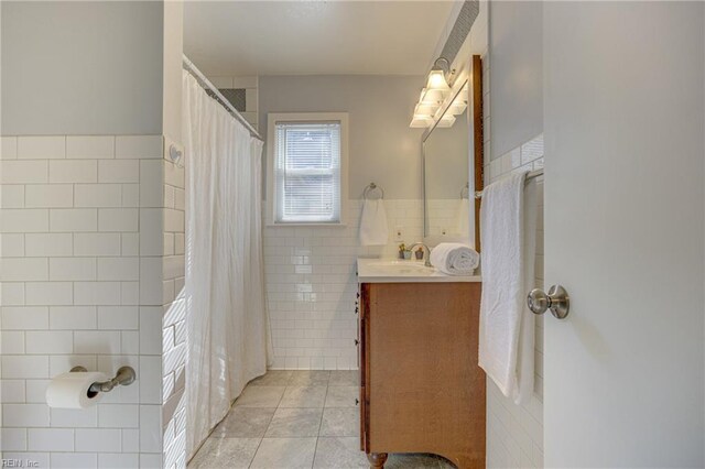 bathroom with tile patterned floors, tile walls, curtained shower, and vanity