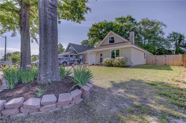 view of front of property with an attached garage, a front lawn, fence, and a chimney