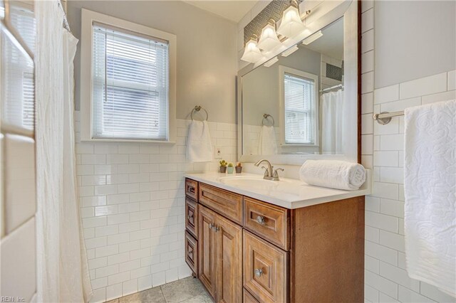 full bathroom featuring tile walls, tile patterned flooring, a wainscoted wall, and vanity