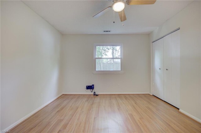 unfurnished bedroom with baseboards, visible vents, wood finished floors, and a closet