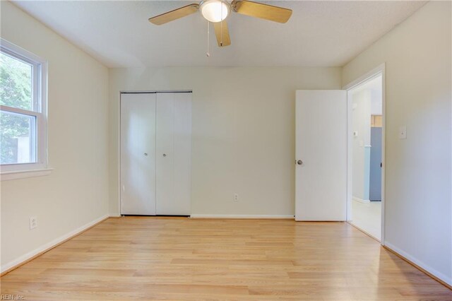unfurnished bedroom featuring baseboards, light wood-style flooring, and a closet