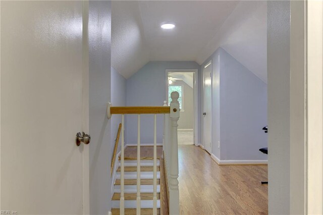 stairway featuring baseboards, wood finished floors, and lofted ceiling