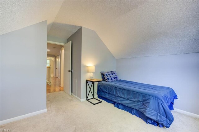 bedroom with carpet floors, a textured ceiling, vaulted ceiling, and baseboards