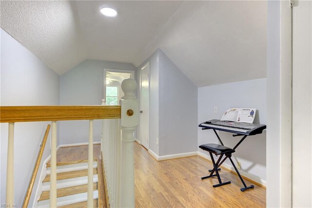 additional living space with baseboards, lofted ceiling, and light wood-style floors