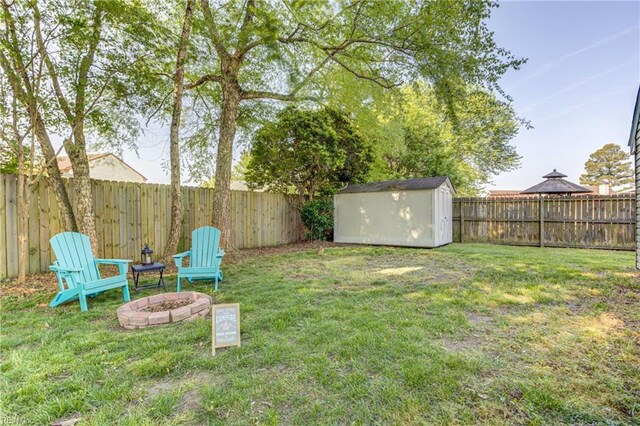 view of yard featuring an outdoor structure, a fenced backyard, a fire pit, and a storage shed