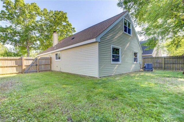 rear view of house with a fenced backyard, central AC unit, a chimney, and a yard