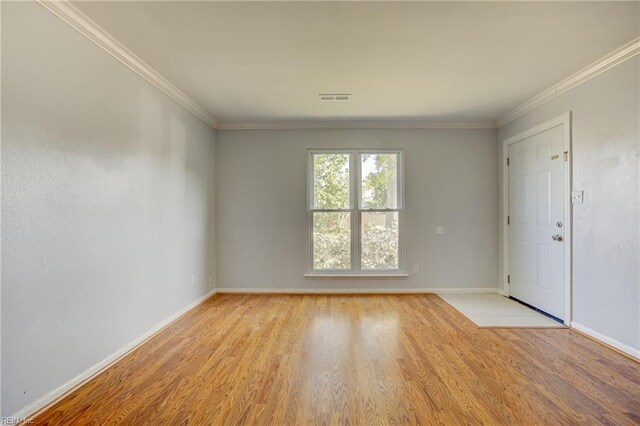 unfurnished room with visible vents, light wood-style floors, crown molding, and baseboards