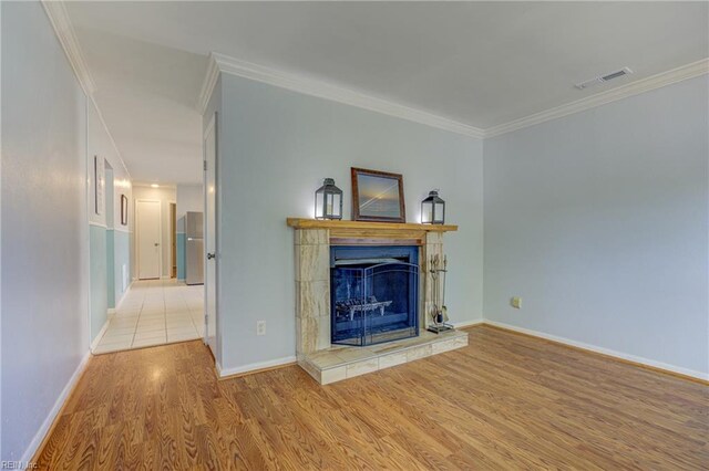 unfurnished living room with light wood-style floors, baseboards, crown molding, and visible vents