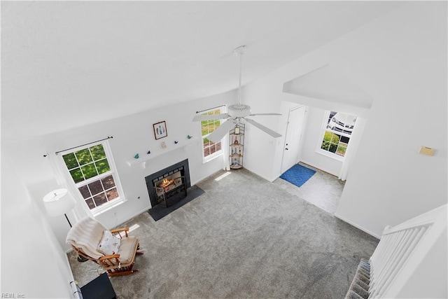 living room featuring carpet flooring, ceiling fan, a fireplace with flush hearth, and lofted ceiling