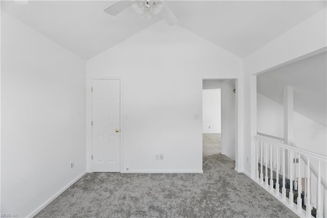 carpeted empty room featuring ceiling fan, vaulted ceiling, and baseboards