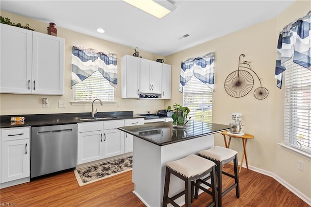 kitchen featuring visible vents, dishwasher, a healthy amount of sunlight, and a kitchen bar