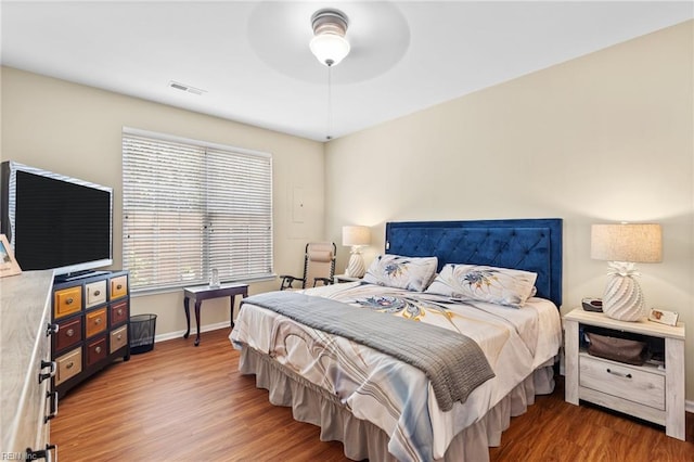 bedroom featuring a ceiling fan, baseboards, visible vents, and wood finished floors