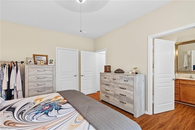 bedroom with a sink, ensuite bath, wood finished floors, and ceiling fan