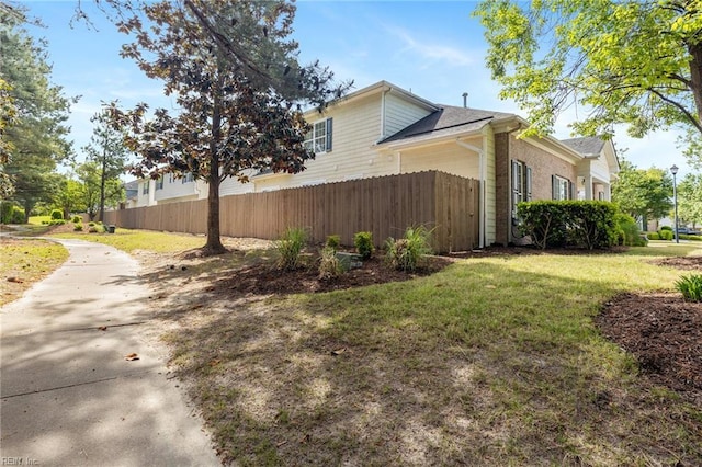 view of home's exterior featuring fence and a lawn
