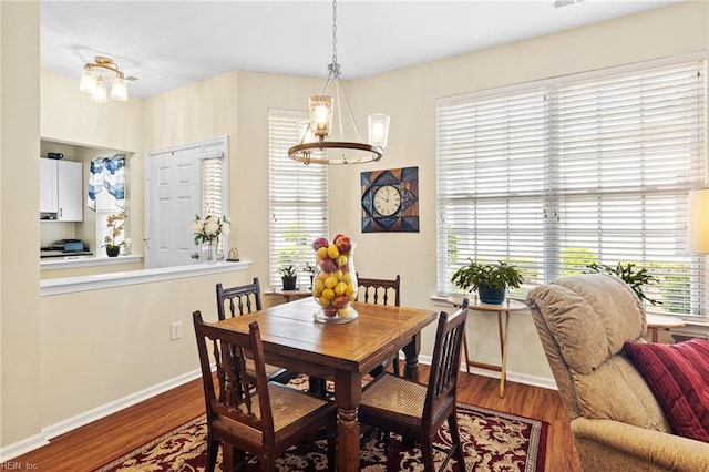 dining room with baseboards, wood finished floors, and a chandelier