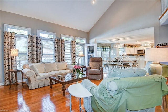living area featuring high vaulted ceiling, light wood-style flooring, and a wealth of natural light
