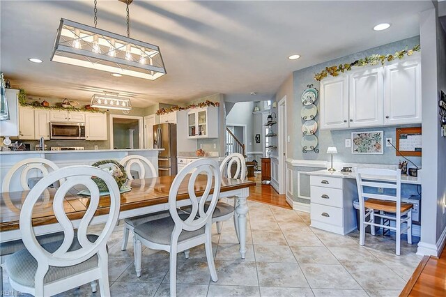 dining area with recessed lighting, light tile patterned floors, and a wainscoted wall