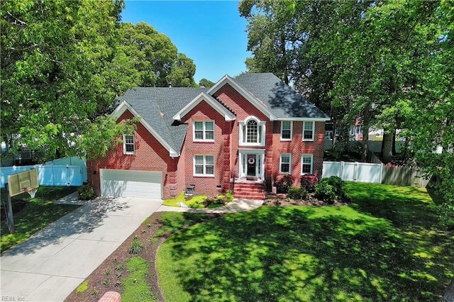 colonial inspired home with a front lawn, fence, brick siding, an attached garage, and driveway
