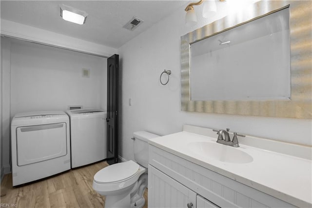1125 Stewart St, Chesapeake, VA 23324 - bathroom with vanity, toilet, wood finished floors, visible vents, and washing machine and dryer