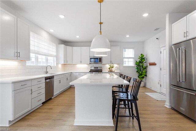 kitchen with a kitchen breakfast bar, a center island, tasteful backsplash, light countertops, and stainless steel appliances