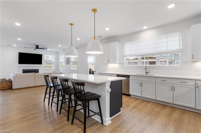 kitchen with a kitchen island, a breakfast bar, ceiling fan, a sink, and dishwasher