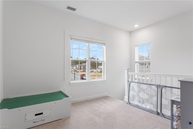 interior space with carpet floors, baseboards, visible vents, and multiple windows