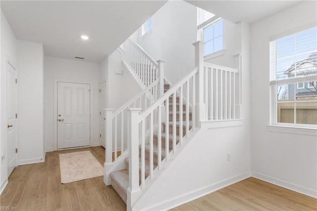 foyer entrance featuring baseboards, stairs, and wood finished floors