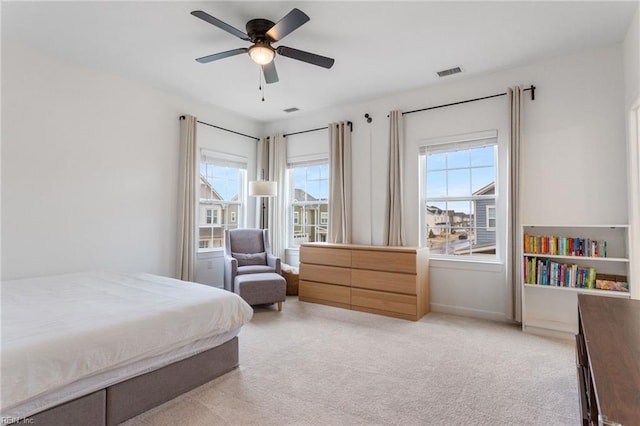 bedroom featuring light colored carpet, a ceiling fan, visible vents, and multiple windows
