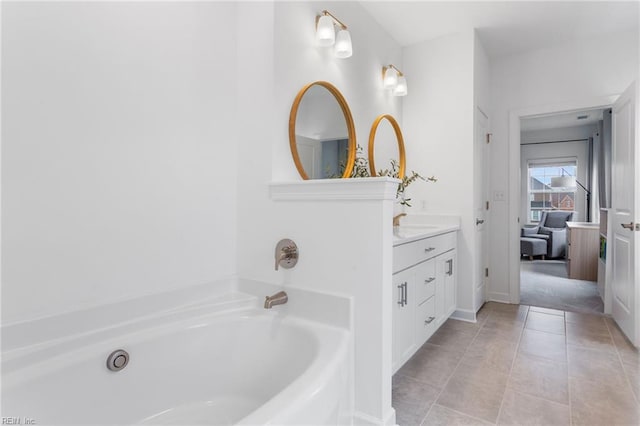 full bath with vanity, tile patterned floors, baseboards, and a garden tub