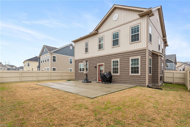 back of property with a fenced backyard, board and batten siding, a yard, and a patio area