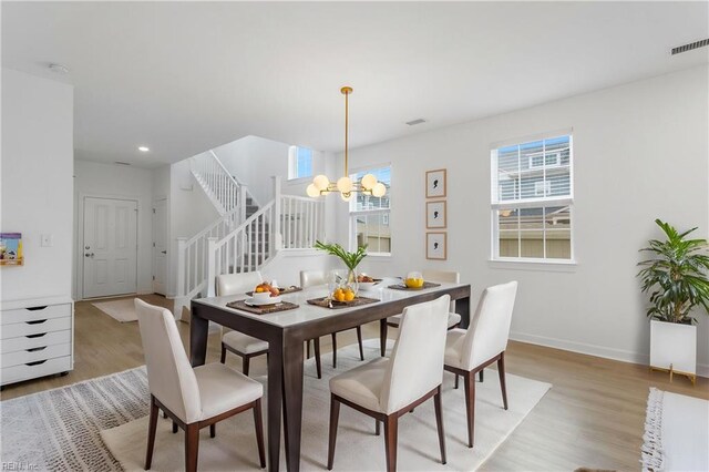 dining area with visible vents, stairs, baseboards, light wood-style floors, and a notable chandelier