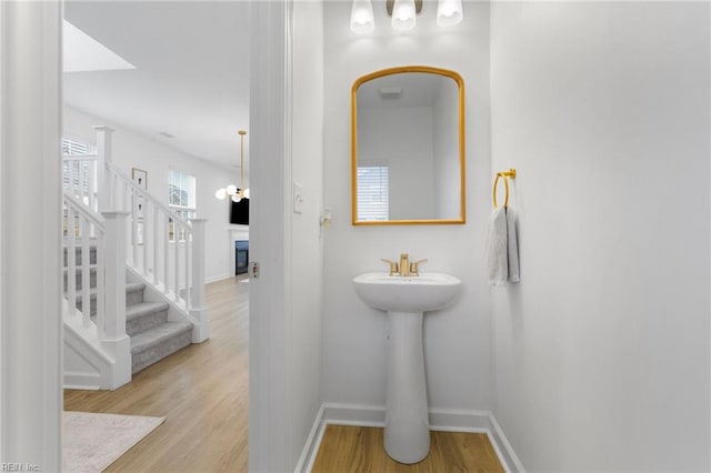 bathroom with a sink, baseboards, a fireplace, and wood finished floors