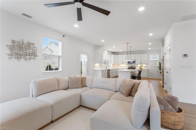 living room with a healthy amount of sunlight, a ceiling fan, recessed lighting, and visible vents