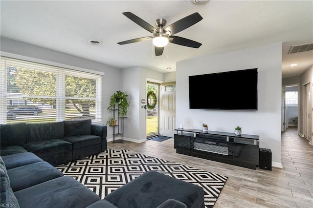 living room with ceiling fan, baseboards, and wood finished floors