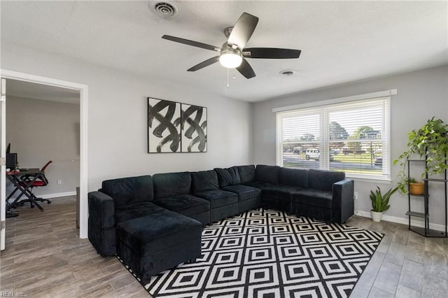 living room featuring a ceiling fan, light wood-style flooring, and baseboards