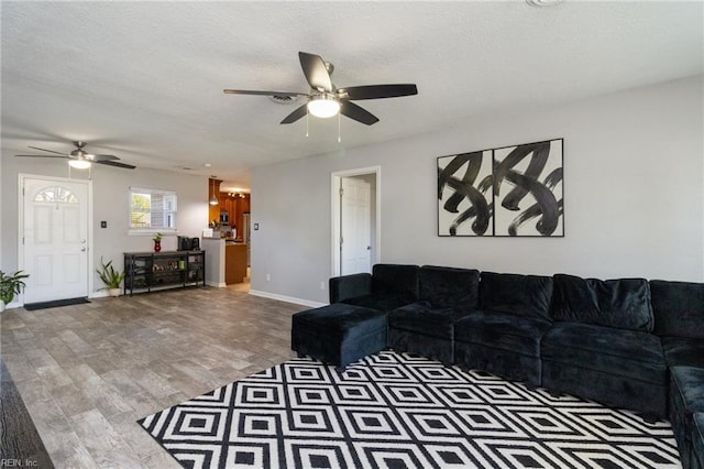 living room with ceiling fan, wood finished floors, and baseboards