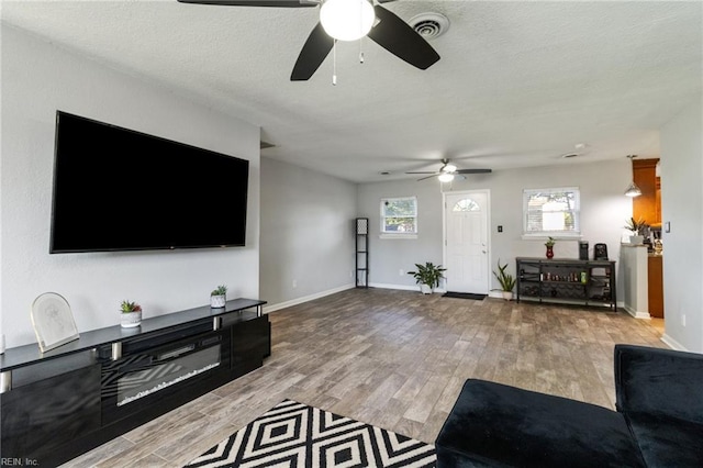 living area with a ceiling fan, wood finished floors, and baseboards