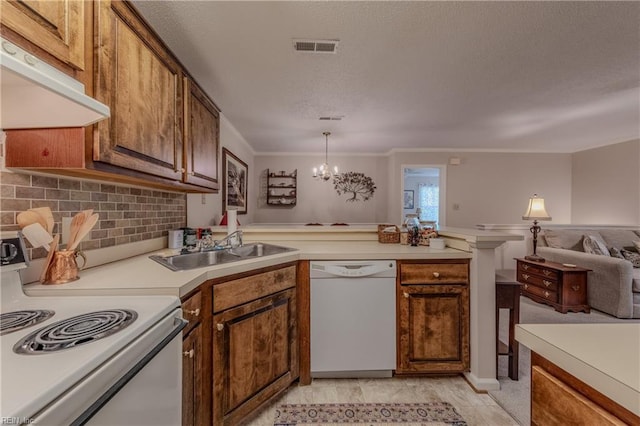 kitchen featuring a sink, ventilation hood, white appliances, light countertops, and a peninsula
