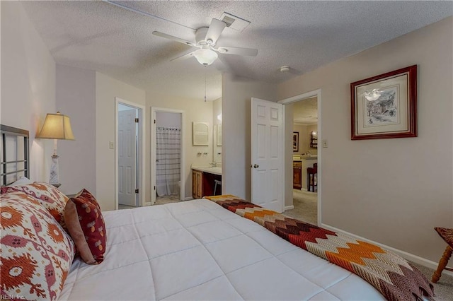 bedroom featuring carpet flooring, ensuite bath, a textured ceiling, baseboards, and visible vents