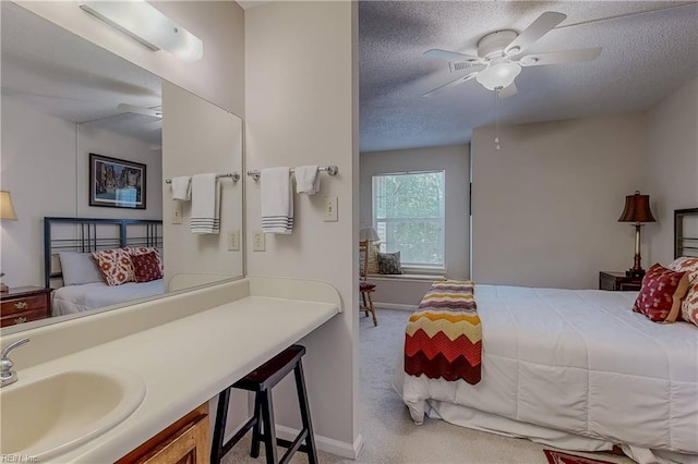 carpeted bedroom featuring baseboards, a sink, a textured ceiling, and a ceiling fan