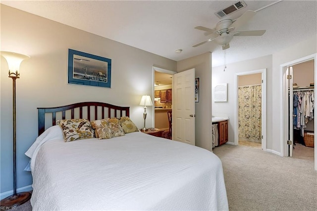 bedroom with visible vents, baseboards, ensuite bathroom, light colored carpet, and a spacious closet